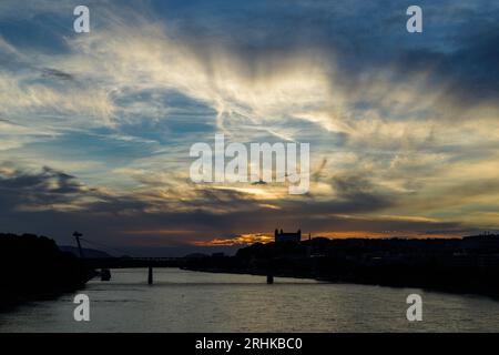 Sunset over Danube river with silhouettes of castle and SNP bridge, known landmarks in Bratislava, capital of Slovakia Stock Photo