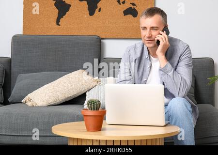 Mature male freelancer talking by mobile phone on sofa at home Stock Photo