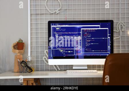 Computer monitor with code at programmer's workplace in office Stock Photo