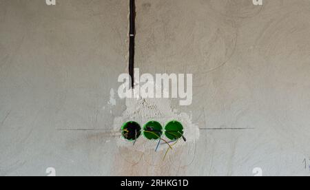 Plastic backbox for sockets or switches inserted into the drilled holes on wall Stock Photo