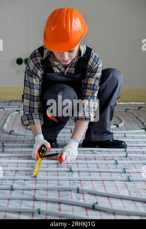 Woman worker takes measurements during the installation of a warm floor. Warm floor heating system. Stock Photo