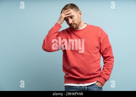Worried man put hand to forehead. Stressed guy with expression of anxiety, disappointment on face Stock Photo