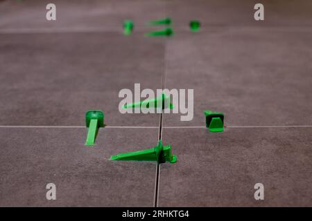 Tile levelling system, four plastic green clips with wedges. Close-up view, selective focus, blurred background Stock Photo