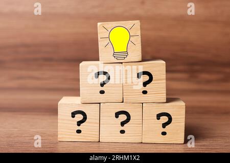 Idea concept. Cubes with illustration of light bulb and question marks on wooden table Stock Photo