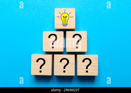 Idea concept. Wooden cubes with illustration of light bulb and question marks on light blue background, flat lay Stock Photo