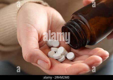 Woman pouring pills from bottle, closeup view Stock Photo