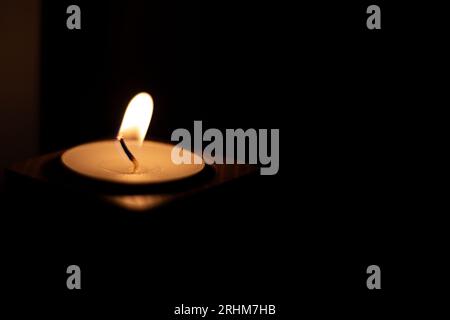 Close-up of flame burning on candle isolated on a black background. Center Stock Photo