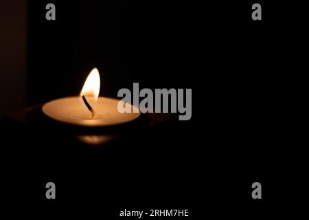 Close-up of flame burning on candle isolated on a black background. Center Stock Photo