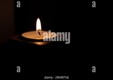 Close-up of flame burning on candle isolated on a black background. Center Stock Photo