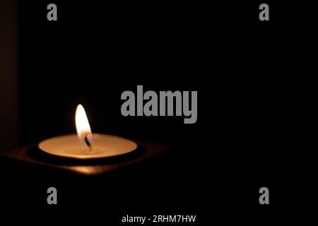 Close-up of flame burning on candle isolated on a black background. Center Stock Photo