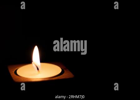Close-up of flame burning on candle isolated on a black background. Center Stock Photo