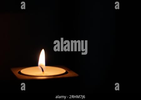 Close-up of flame burning on candle isolated on a black background. Center Stock Photo