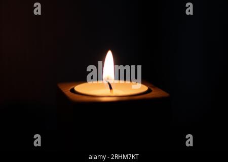 Close-up of flame burning on candle isolated on a black background. Center Stock Photo