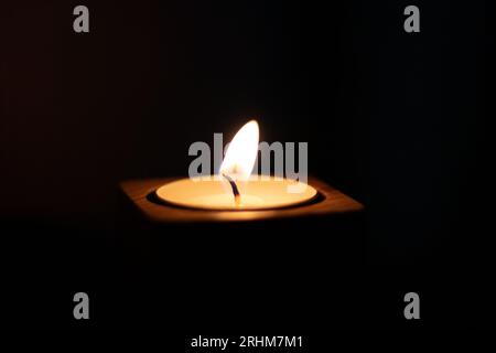 Close-up of flame burning on candle isolated on a black background. Center Stock Photo
