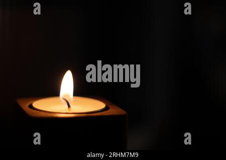 Close-up of flame burning on candle isolated on a black background. Center Stock Photo