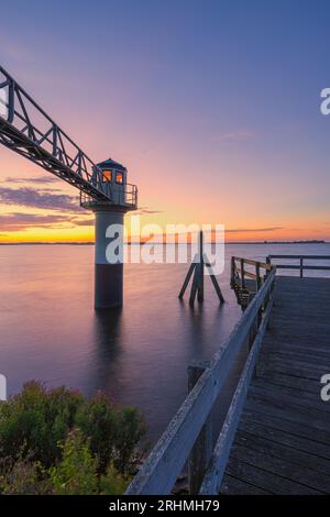 A vertical photo of a summer sunrise at the lighthouse in Oostmahorn. However, the name lighthouse is not appropriate here, because it is a measuring Stock Photo