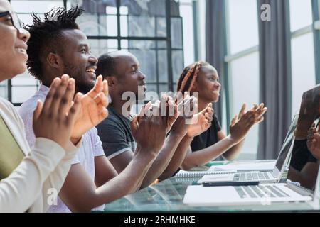 Multi ethnic business group greets somebody with clapping and smiling Stock Photo