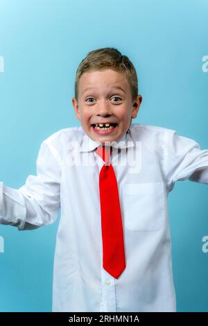 a happy funny first grader in a white shirt with a red tie is laughing. Cute Caucasian boy goes to school. Schoolboy. September 1, for the first time Stock Photo