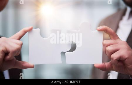 Working together to put things together. two unrecognizable businesspeople fitting puzzle pieces together in studio Stock Photo