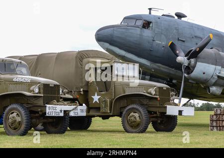 US Second World War military vehicles alongside a Douglas C-47 Skytrain transport plane & equipment, recreating D-Day loading at Rougham Airfield Stock Photo