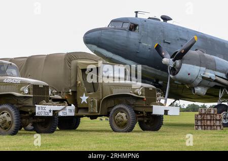 US Second World War military vehicles alongside a Douglas C-47 Skytrain transport plane & equipment, recreating D-Day loading at Rougham Airfield Stock Photo