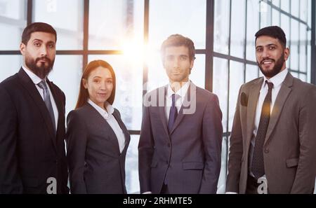 Businessmen with brunette in group posing in office lobby Stock Photo