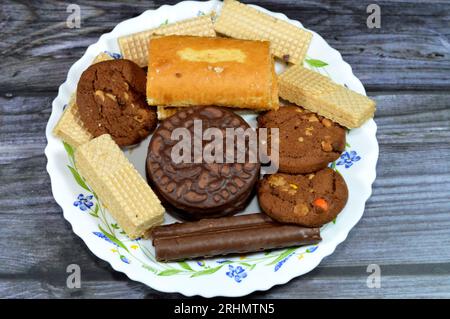 A candy plate with Chocolate sticks, crunchy wafers with chocolate cream filling, wafers crunchy biscuits filled with vanilla, Swiss roll cake filled Stock Photo