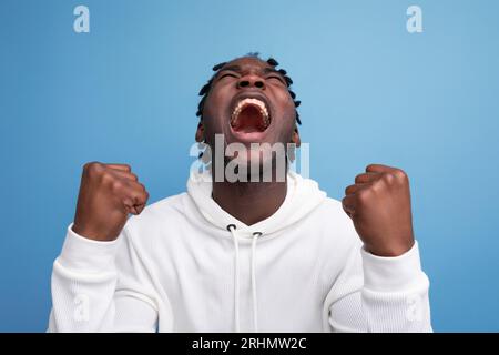 joyful energetic happy dark-skinned young brunette man in a white sweatshirt on the background with copy space Stock Photo
