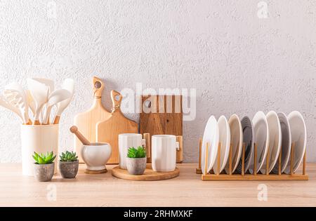 Various stylish white ceramic tableware on wooden kitchen countertop. A set of wooden cutting boards. Eco items in the kitchen. front view Stock Photo