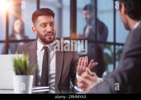Two medium focused business workers communicate in the office. Stock Photo