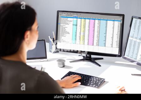 Side View Of Businesswoman's Hand Analyzing Data On Computer Over Desk Stock Photo