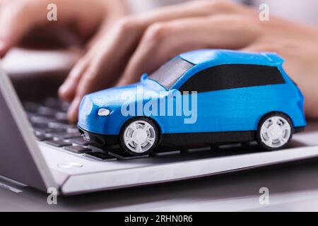 Close-up Of A Small Blue Car On Laptop Keypad Stock Photo