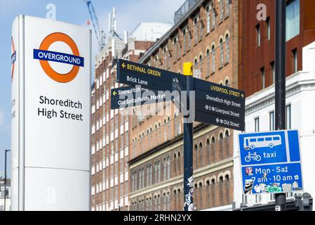 Shoreditch High Street Overground sign and directional street signs in East London, pointing to Brick Lane and Liverpool Street Station. Stock Photo