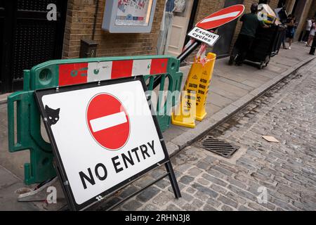 Pedestrians walk past the bent and damaged No Entry sign post on Neal Street, on 13th August 2023, in London, England. Stock Photo