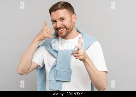 Man smiles and gestures to call him. Gesture of telephone receiver. Request to leave number Stock Photo