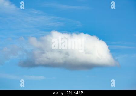 Single white fluffy cloud formation in blue sky on sunny day Stock Photo