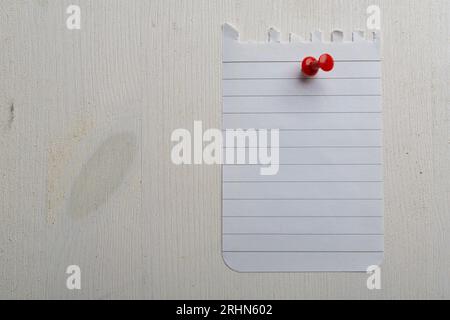 Notebook sheet hung with a red pushpin on a wooden wall Stock Photo