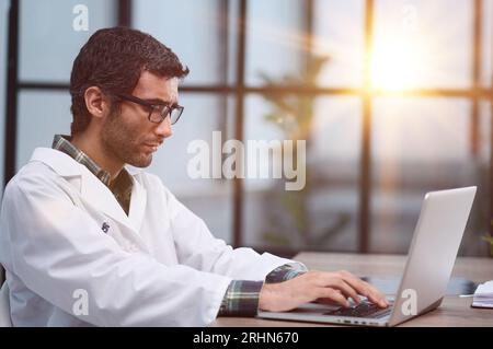 doctor works on a laptop in his office Stock Photo
