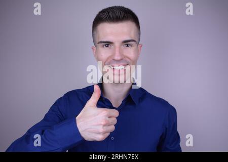 Elegant Smiling Handsome Young Caucasian Man Giving Thumbs Up Gesture on Isolated Background Stock Photo