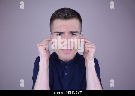 Handsome Caucasian Man Covering Ears with Fingers on Isolated Background Stock Photo