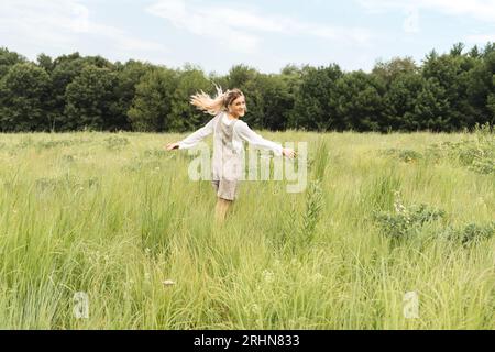 A woman in a romper dancing in a field of grass Stock Photo