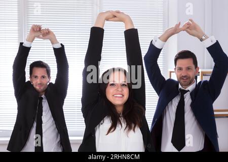 Young Businesspeople Doing Stretching Exercise At Workplace Stock Photo