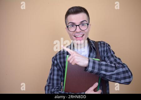 Caucasian Young Handsome Smiling Student in Glasses Points His Finger to the Side Stock Photo