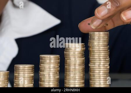 Close-up Of A Smiling African Businesswoman Making Stack Of Coins Stock Photo