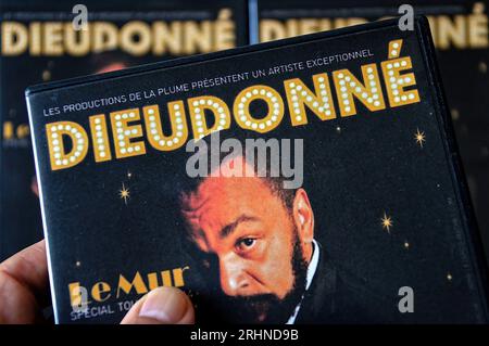 In this photo illustration, a hand of a person holds a DVD of the humorist Dieudonné M'bala M'bala, well known by his stage name Dieudo. In order to guarantee respect for public order, the town hall of Lyon has signed an order prohibiting a show by the comedian Dieudonné scheduled for August 19, 2023. The town hall of Lyon recalled that the comedian was the subject of numerous criminal convictions for having made Holocaust denial speeches, inciting racial hatred, or advocating terrorism. Representations of this same show, entitled 'Sous Bracelet' have already been banned in other cities includ Stock Photo