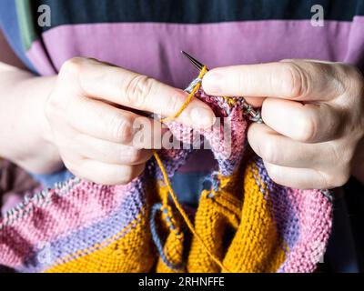 front view of knitting sweater from woolen yarn on steel knitting needles close up Stock Photo