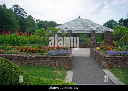 A pretty stone and wood gazebo at the end of a flower bed in a local garden park -15 Stock Photo
