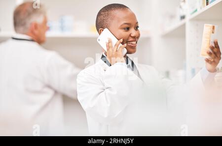 Pharmacy, phone call and woman with medicine box while reading information. African person or pharmacist talking on smartphone for telehealth Stock Photo