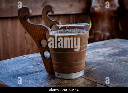 Two wooden mugs with fermented sheep milk on the table. Shepherd hut in Pieniny mountains, Poland. Stock Photo