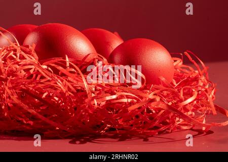 Colored eggs symbolize Easter in shades of red on straw Stock Photo